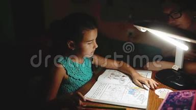 小女孩晚上做家庭作业读一本书和作家。 晚上做家庭作业女孩课从